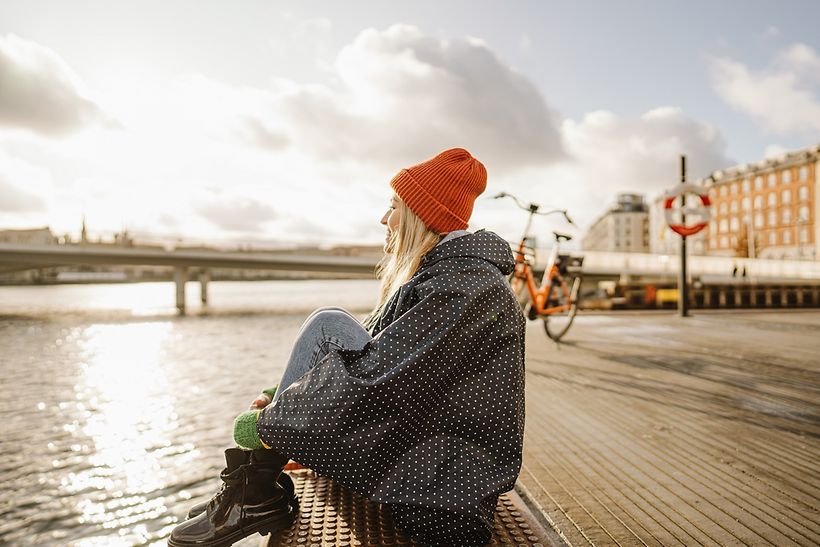 Junge Frau sitzt in Kopenhagen am Wasser