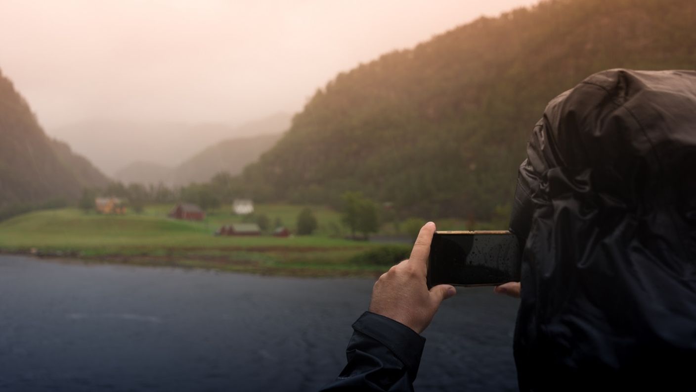 Jemand macht ein Handyfoto von einem Fjord bei Bergen in Norwegen