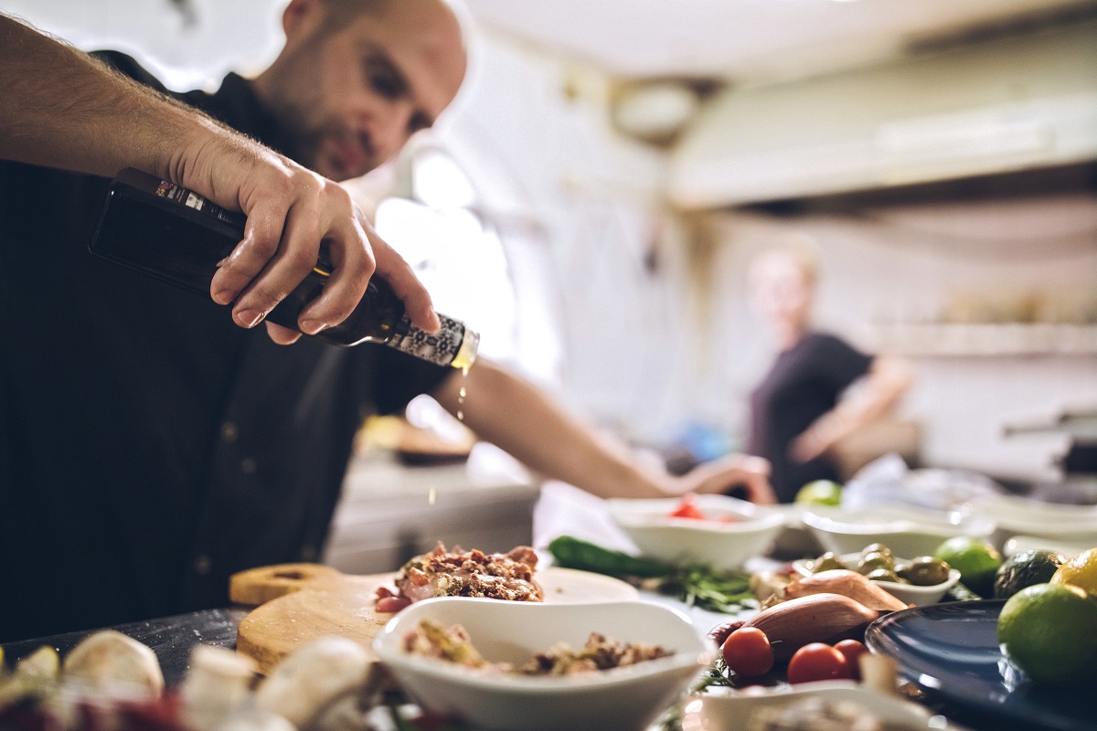 Mann gießt Öl über Gerichte in einem Restaurant auf Malta