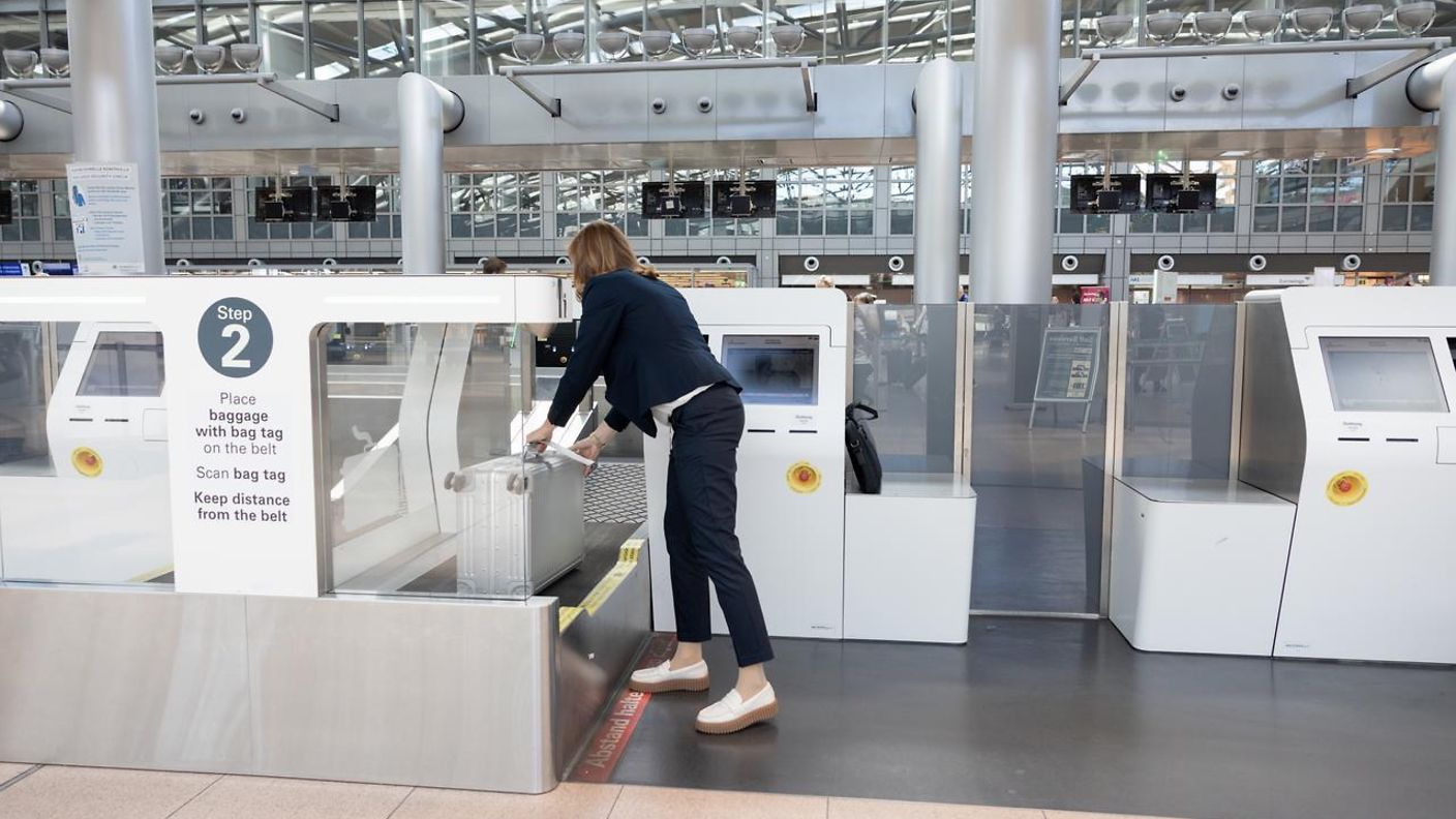 Frau steht vor dem Self-Bag-Drop-Automaten und legt ihr Gebäckstück auf der Seite liegend auf das Kofferband.