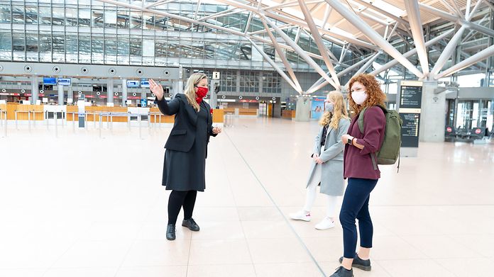 Servicepersonal und Reisende mit Maske im Terminal