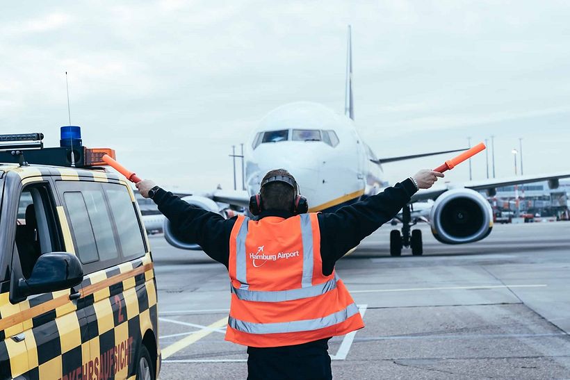 Mann auf Vorfeld weist Flugzeug ein