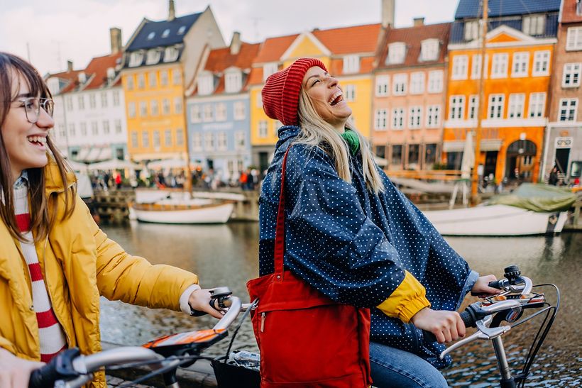 Junge Frauen fahren lachend mit dem Fahrrad durch Kopenhagen