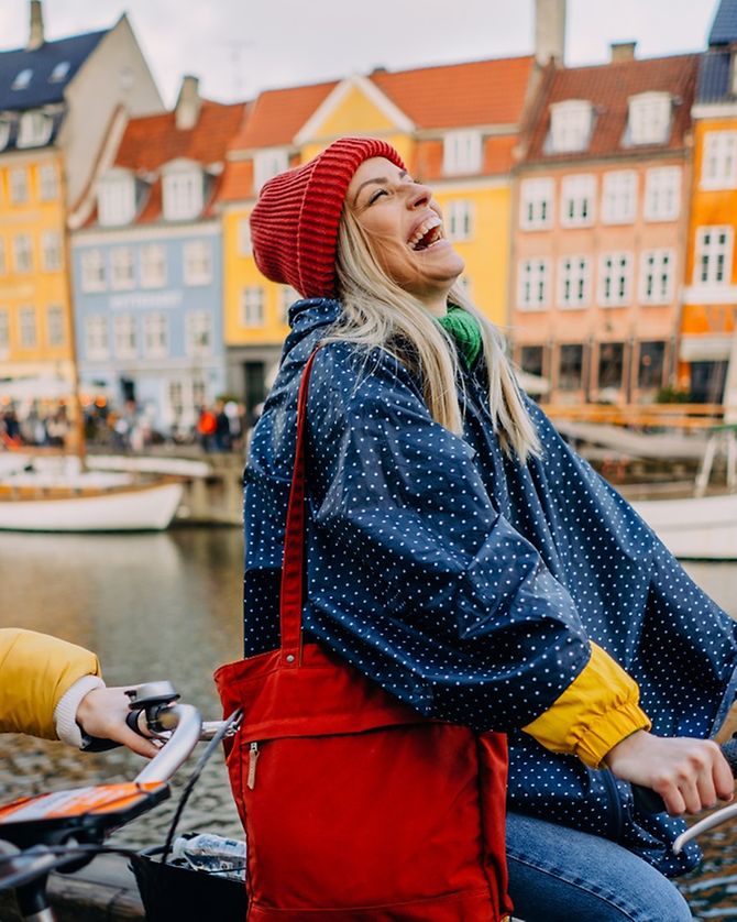Junge Frauen fahren lachend mit dem Fahrrad durch Kopenhagen