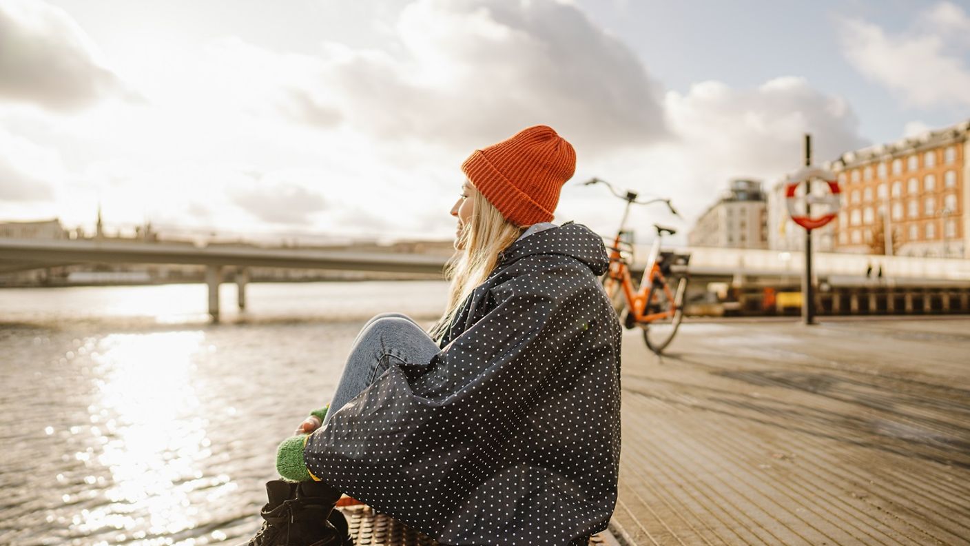 Junge Frau sitzt in Kopenhagen am Wasser