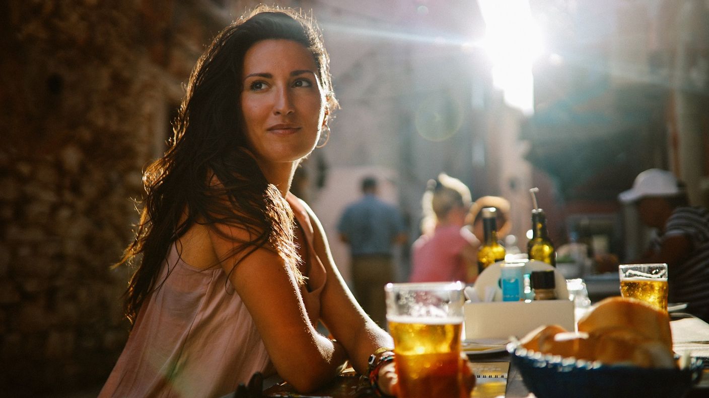 Eine Frau wartet an einem Restaurant-Tisch auf ihr Essen