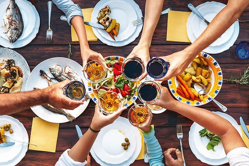 Anstoßen an einem reich gedeckten Tisch mit Essen