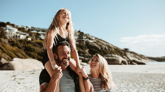 Lachende Familie am Strand im Urlaub