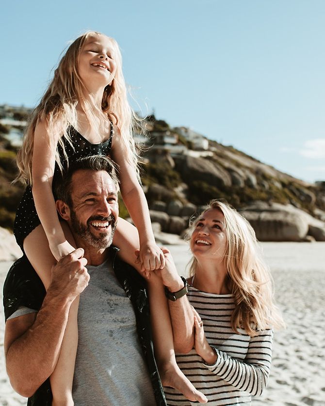 Lachende Familie am Strand im Urlaub