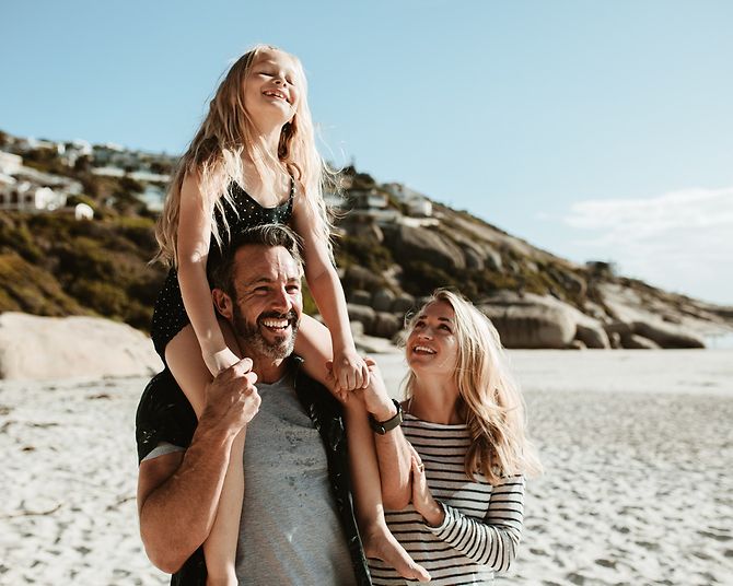 Lachende Familie am Strand im Urlaub