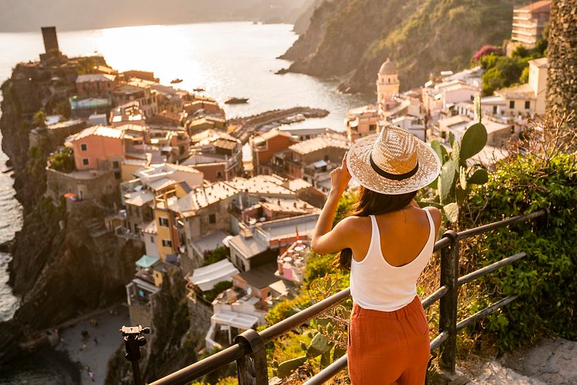 Frau mit Sonnenhut sieht im Urlaub von einem Berg auf eine Altstadt