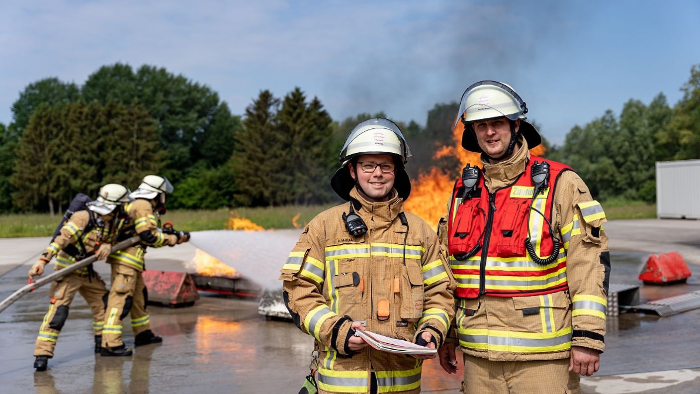 Zwei Feuerwehrleute vor der einer Übung der Flughafenfeuerwehr