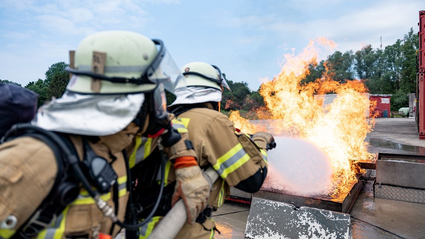 Zwei Feuerwehrleute löschen einen Brand