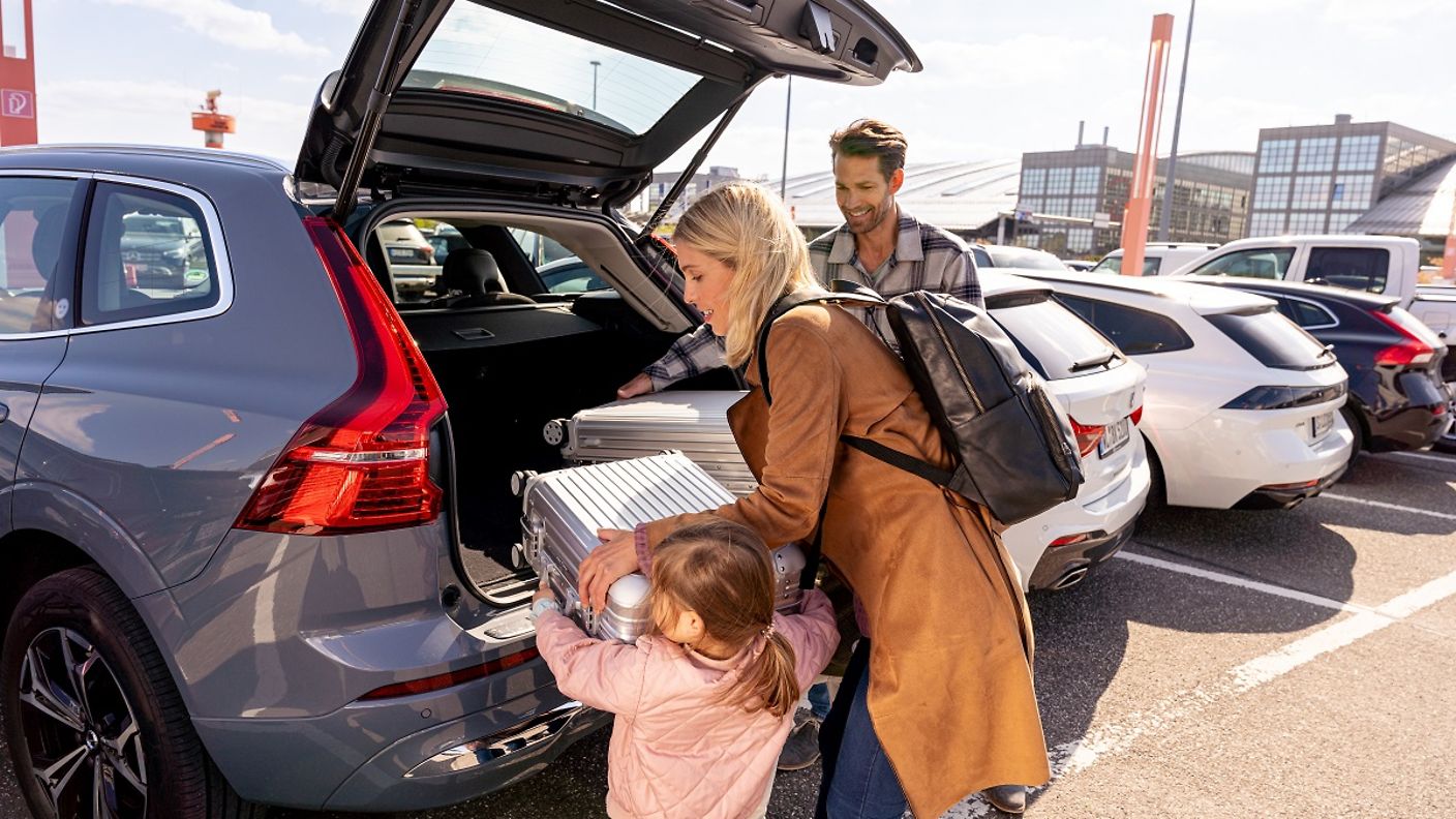 Familie räumt auf dem Parkplatz am Flughafen ihr Gepäck aus dem Kofferraum