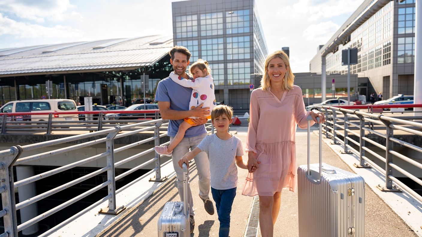 Familie mit Koffern auf dem Weg zum Terminal
