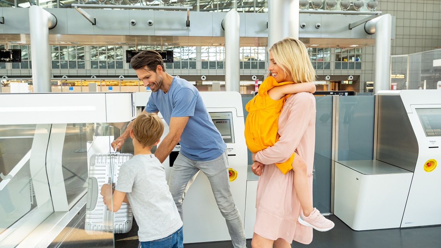 Eine Familie gibt beim Vorabend-Check-in ihren Koffer auf