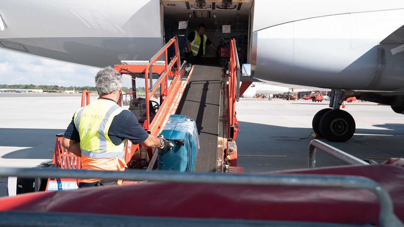 Koffer werden mit einem Transportband in ein Flugzeug geladen