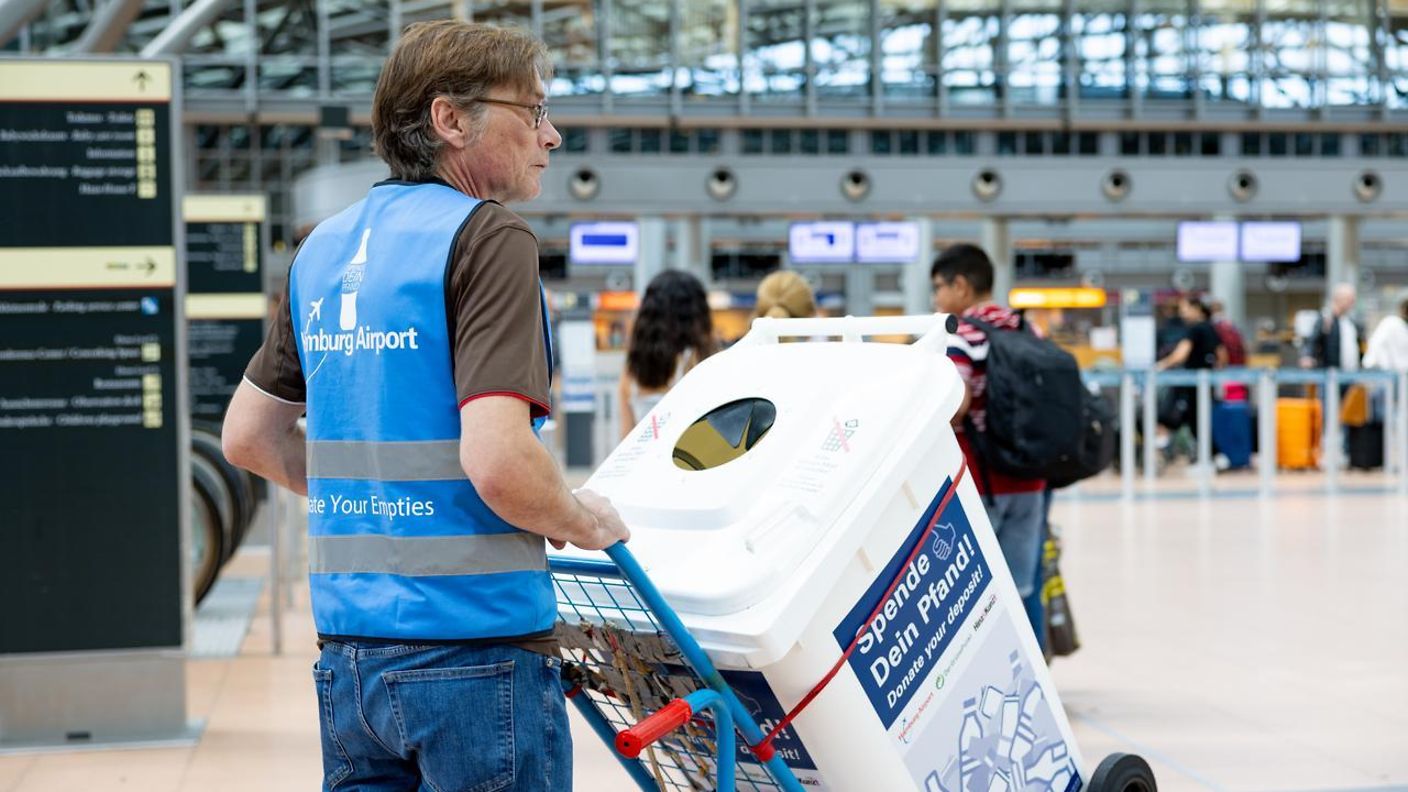 Uwe Tröger, Teamleiter der Leergutbeauftragten, präsentiert die „Spende deinen Pfand“-Tonne im Terminal 2.