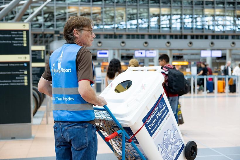 Uwe Tröger, Teamleiter der Leergutbeauftragten, präsentiert die „Spende deinen Pfand“-Tonne im Terminal 2.
