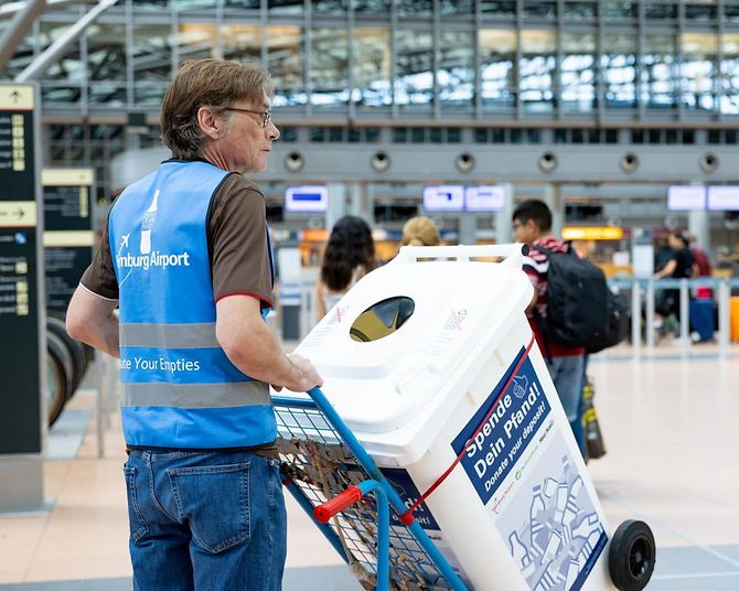 Uwe Tröger, Teamleiter der Leergutbeauftragten, präsentiert die „Spende deinen Pfand“-Tonne im Terminal 2.