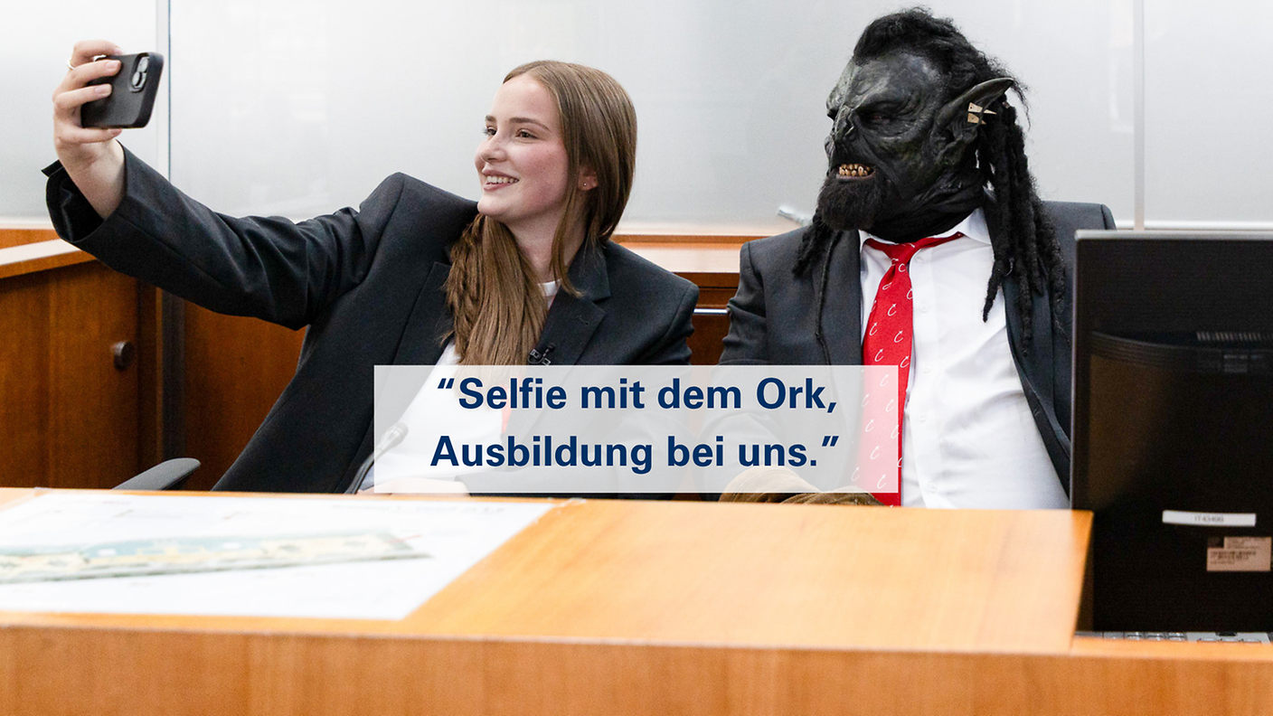 Azubine und Ork in Hamburg Airport Uniform posieren für ein Selfie mit dem Slogan „Selfie mit dem Ork, Ausbildung bei uns“